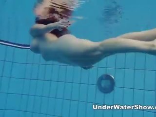 Redheaded característica nadando desnuda en la piscina